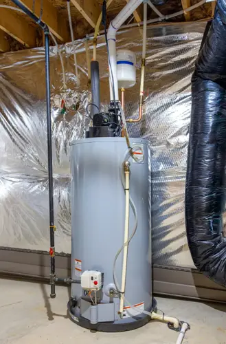A newly installed water heater in a basement with visible pipes and connections, surrounded by insulation material on the walls.